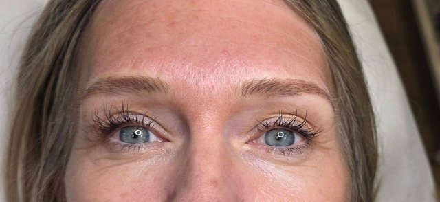 Healed permanent brows framing a client's eyes, photographed straight on.